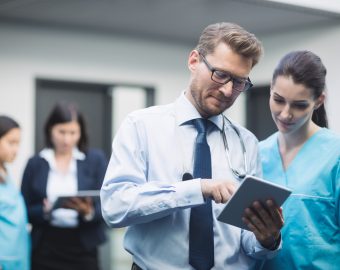 Doctor and nurse discussing over digital tablet in hospital corridor